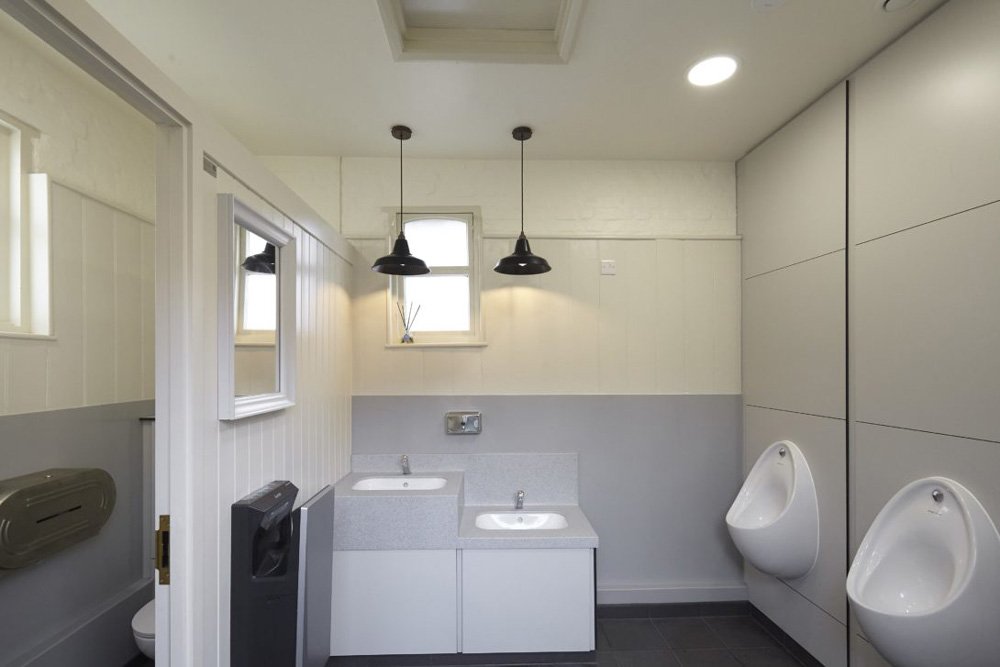 washroom with a toilet cubicle, urinals and vanity unit with corian tops and a lower height station at hughenden manor.jpg