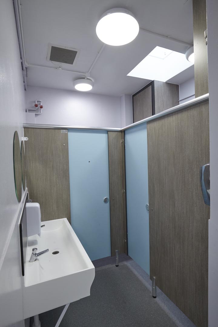 blue and grey woodgrain toilet cubicles and hand wash trough at churchmead.jpg