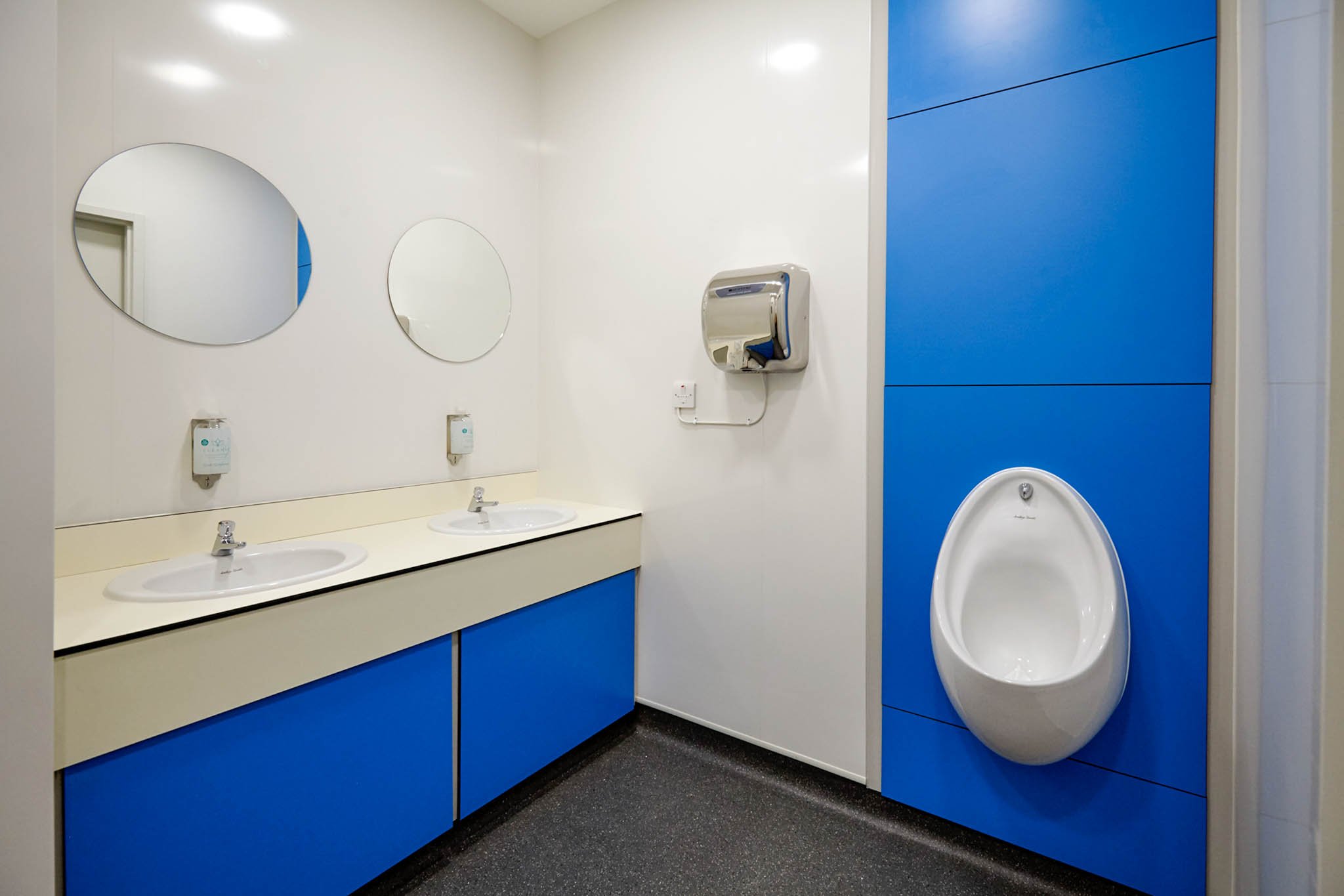 blue duct panel with urinal and a vanity unit with sinks and mirrors above at national maritime museum.jpg