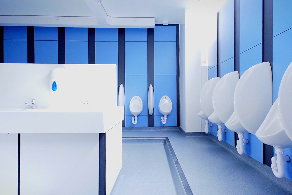 double sided hand wash station and urinals and blue duct panels around the edge of a washroom at lycee francais.jpg