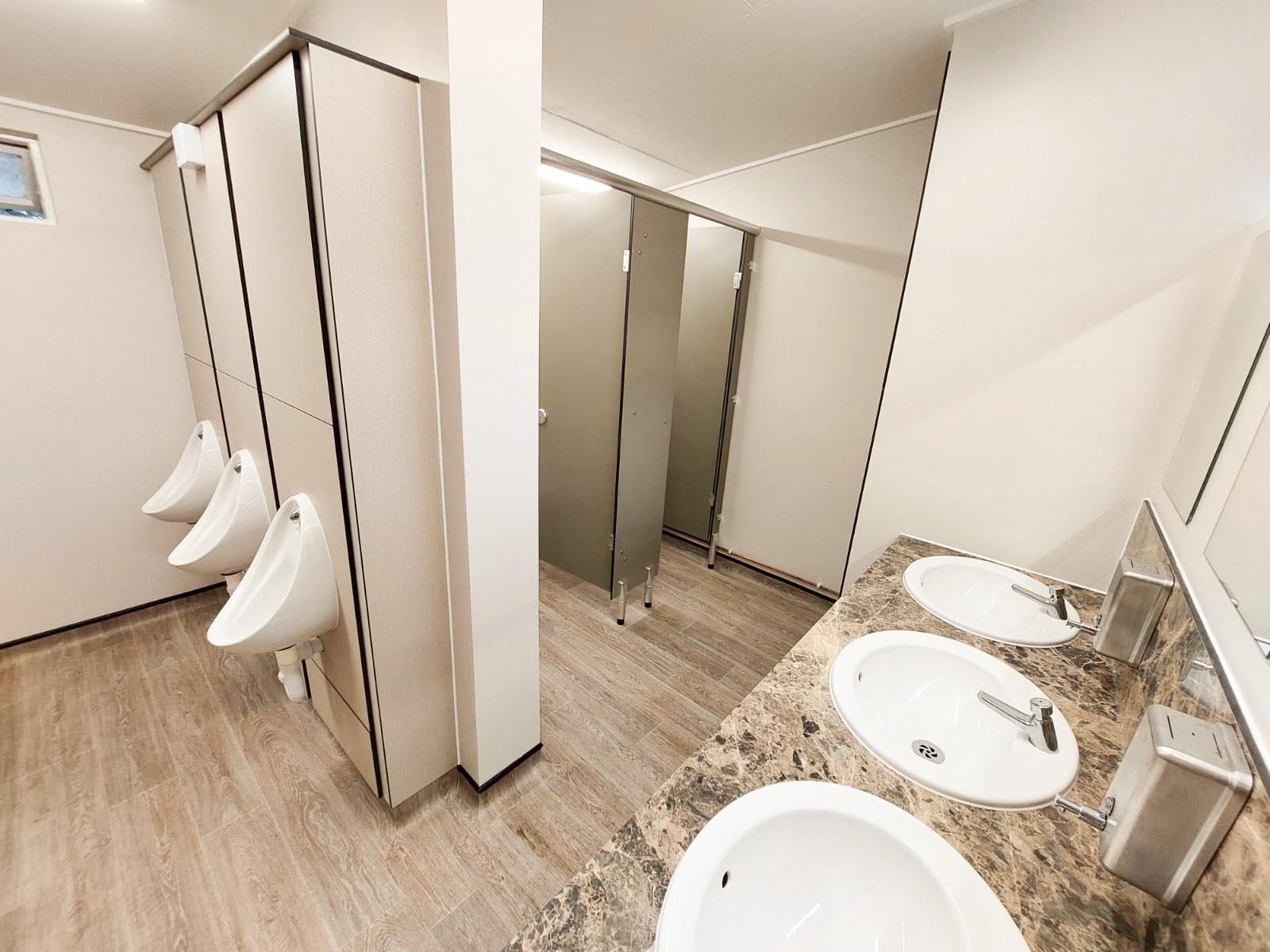 a male washroom with urinals, cubicles and vanity unit hand wash area in green colour scheme at howletts zoo.jpg