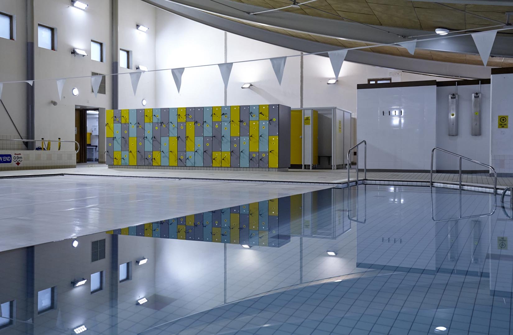 view of a swimming pool with poolside changing rooms and lockers in the background at faringdon leisure centre.jpg