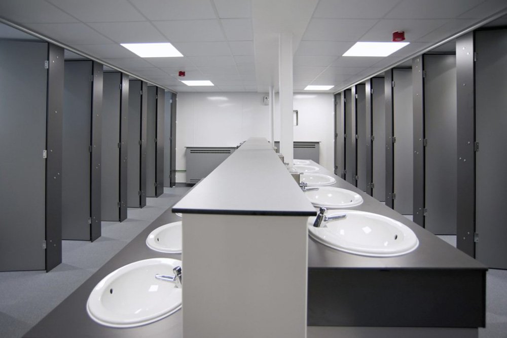 large grey unisex washroom with communal hand wash area with sinks and full height privacy cubicles at princes risborough school.jpg