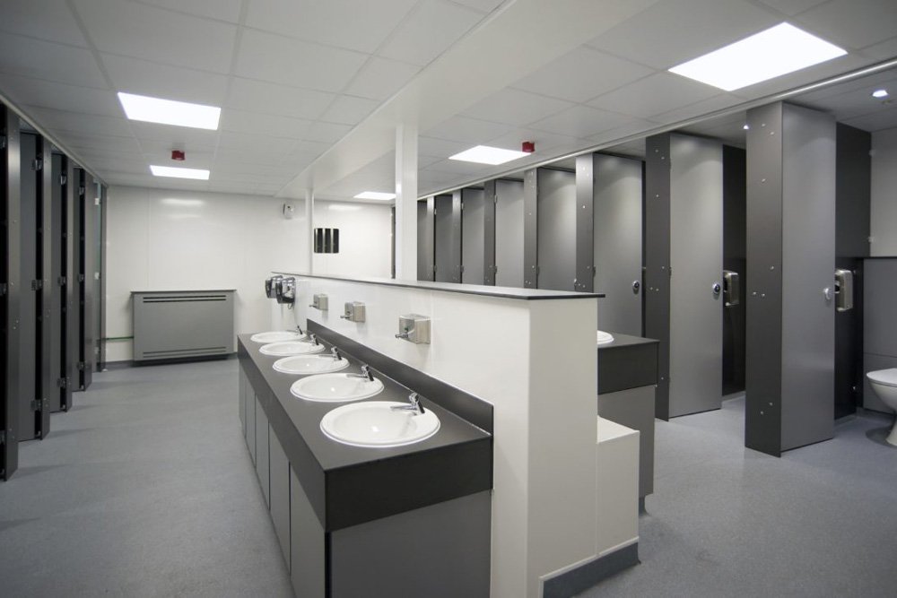 a large unisex washroom with communal hand wash stations and full height privacy cubicles in grey at princes risborough school.jpg