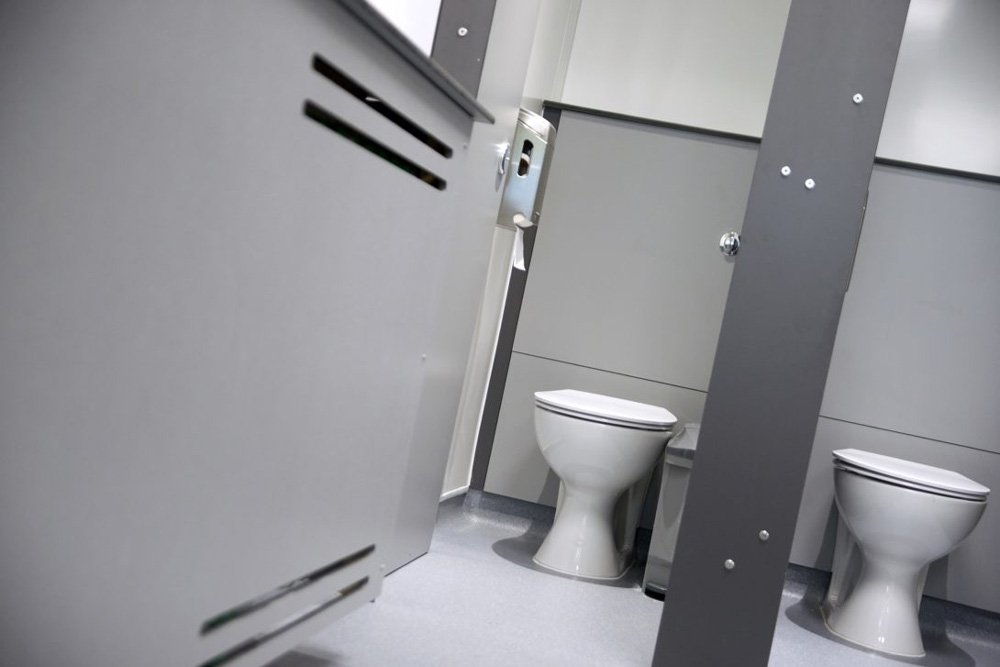 a grey radiator cover and two toilet cubicles with grey half heigh duct panels at princes risborough school.jpg