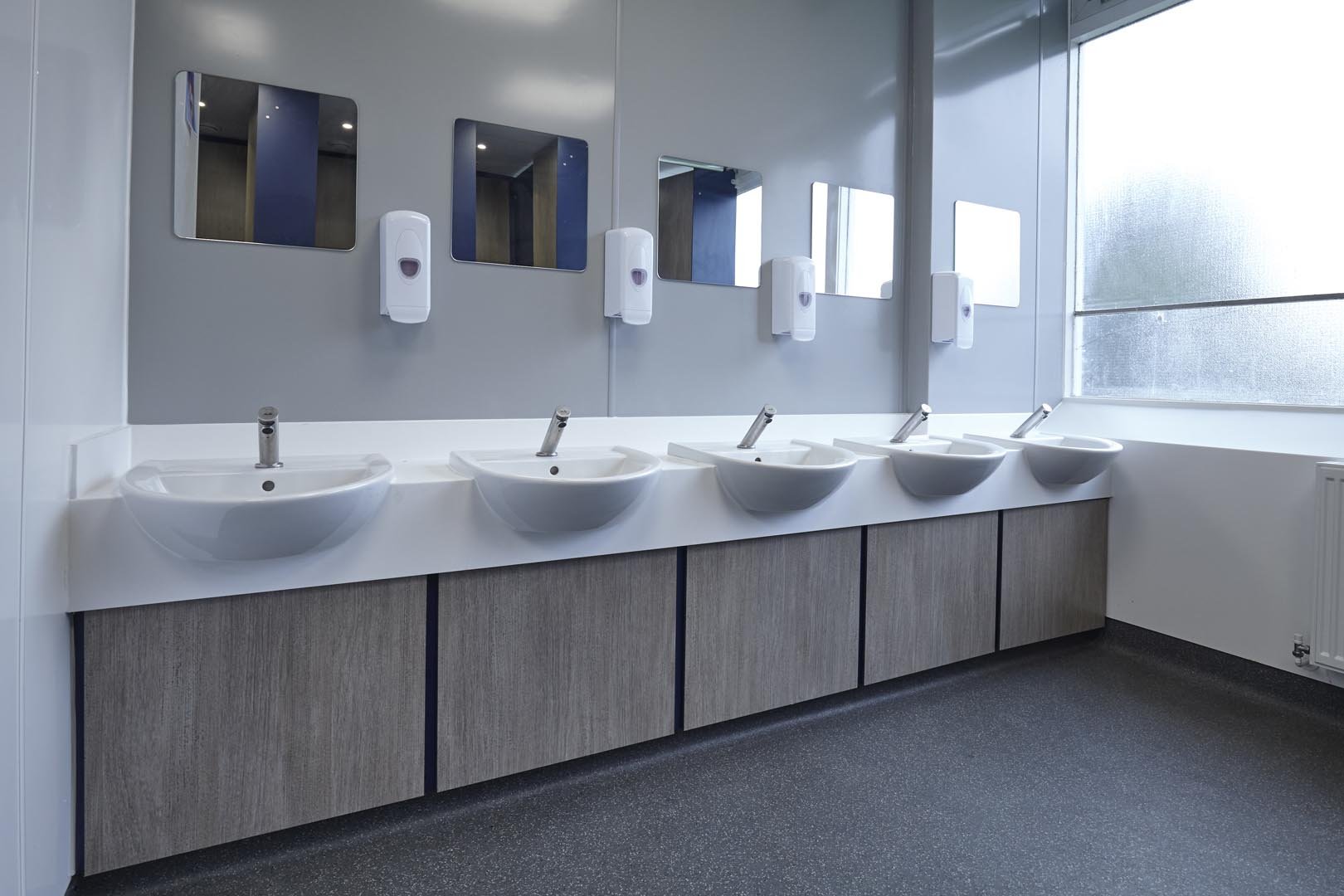 row of sinks on a vanity unit in woodgrain and mirrors at collingwood college.jpg
