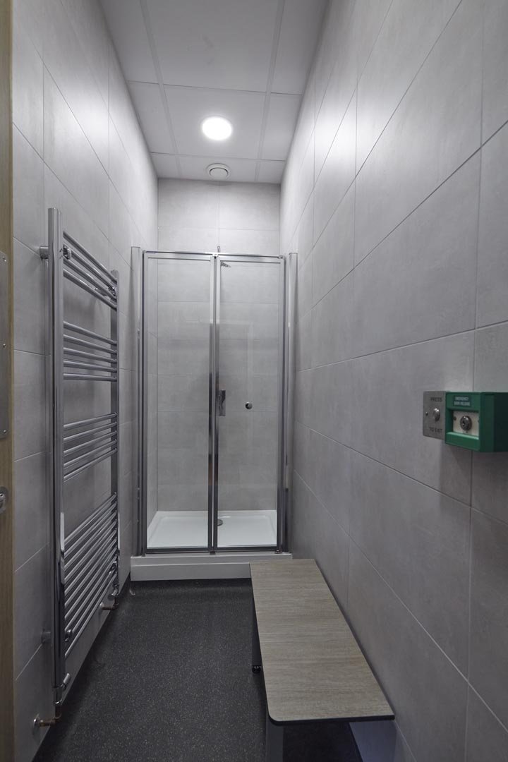 Staff shower room with grey tiling and a bench at collingwood college.jpg