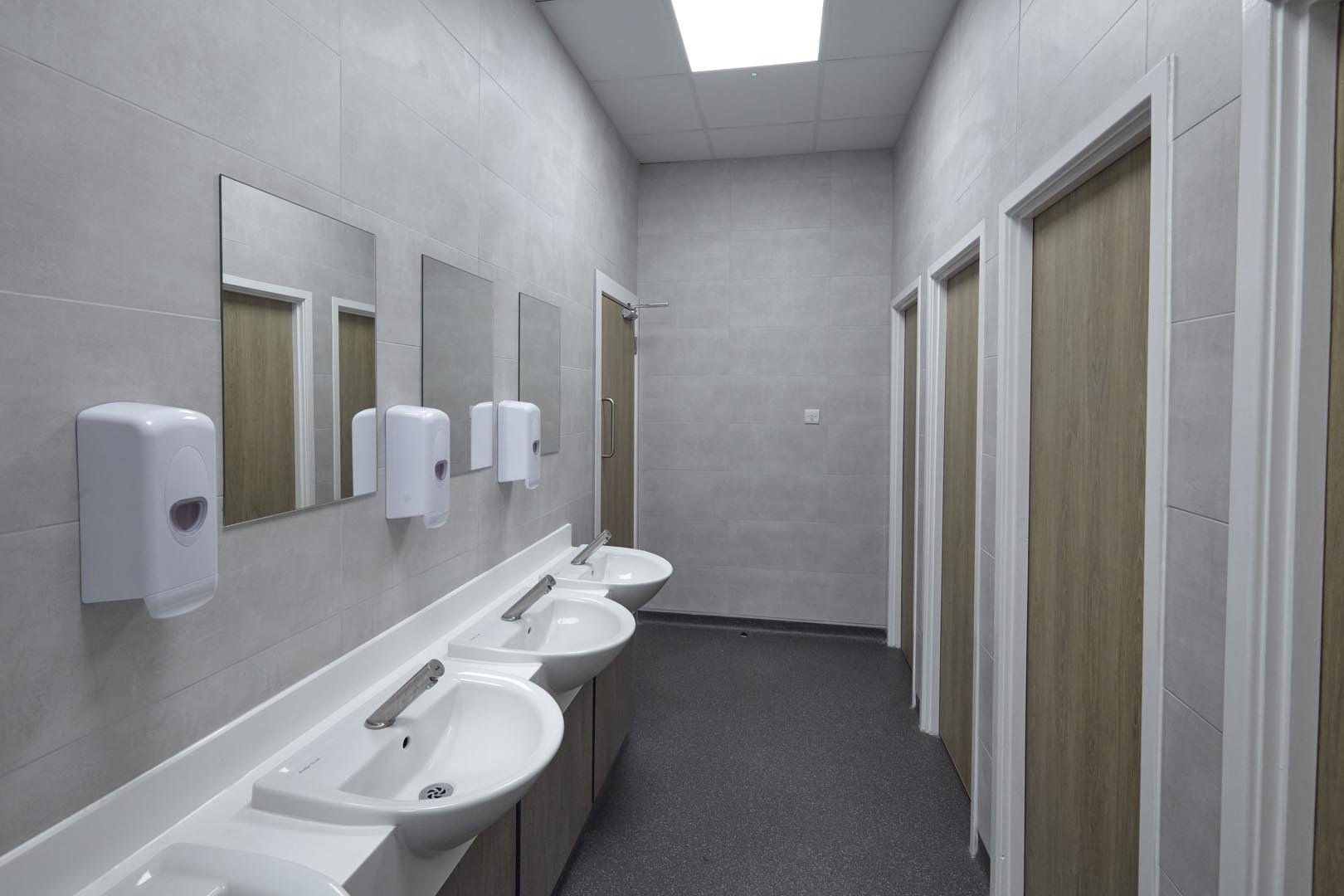 unisex staff toilets with woodgrain doors and vanity units at collingwood college.jpg