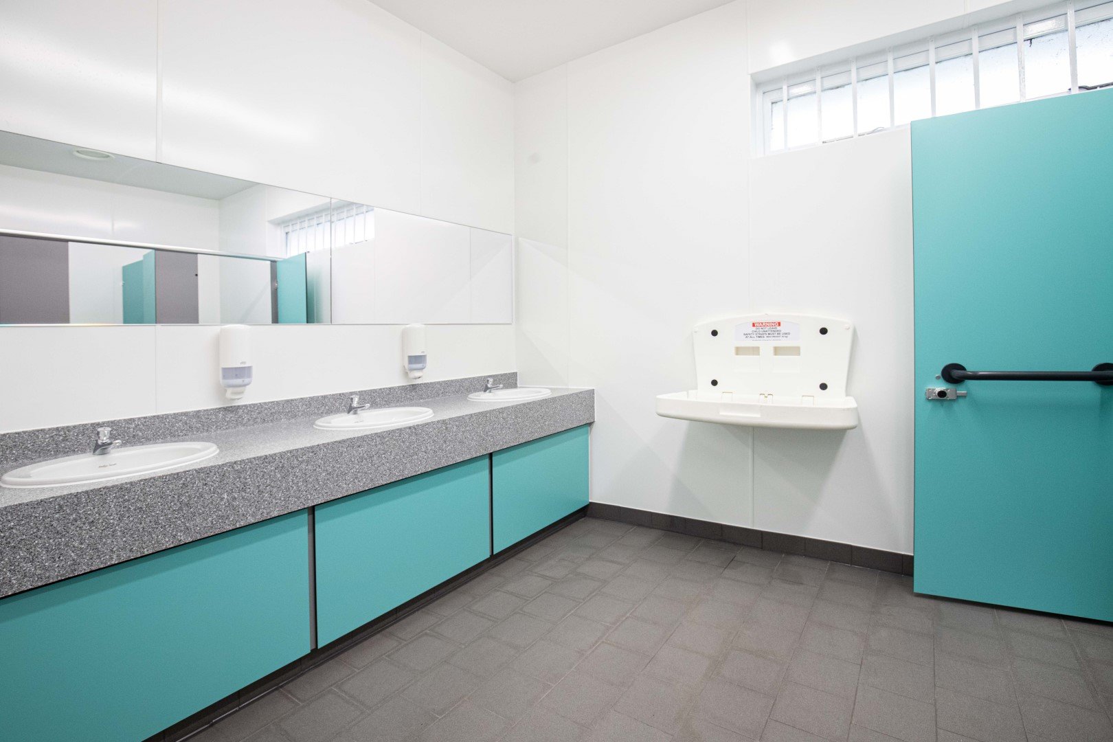 washroom at riverside campsite with row of vanity units in blue and a solid surface top.jpg