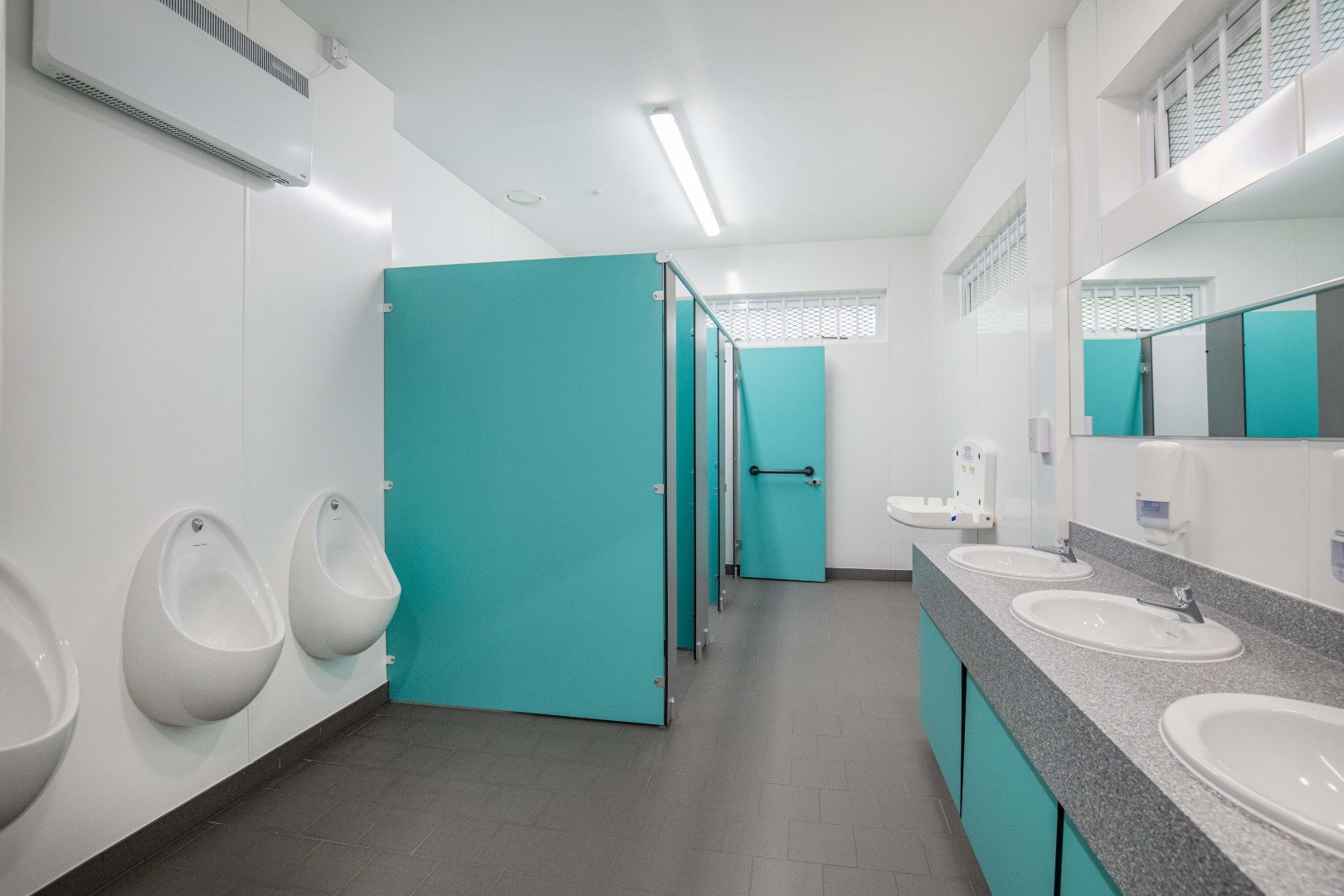 washroom with urinals, toilet cubicles, vanity with solid surface top at riverside campsite.jpg