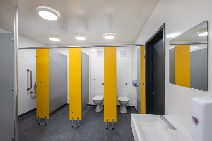 row of yellow and grey toilet cubicles with hygipod ips ducting in white in blyburgate public toilets.png