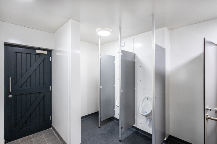 wooden black entrance doors and urinals with partitions at blyburgate public toilets.png