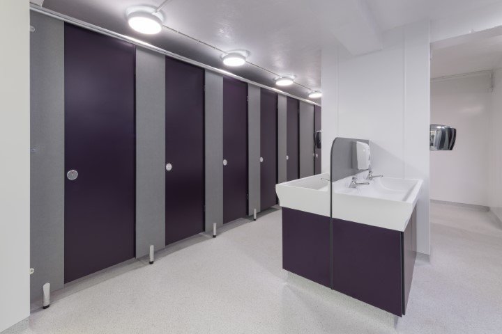 row of purple toilet cubicles with a hand wash area at fakenham academy.jpg