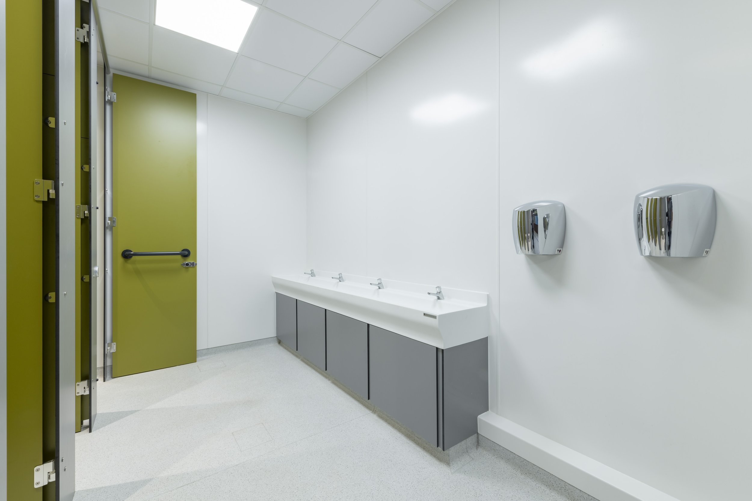 unisex toilet with green privacy toilet and a hand wash area with troughs and hand dryers.jpg