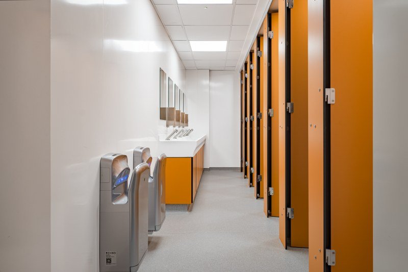 a school washroom with orange colour scheme and privacy cubicles at ashcombe school.jpg