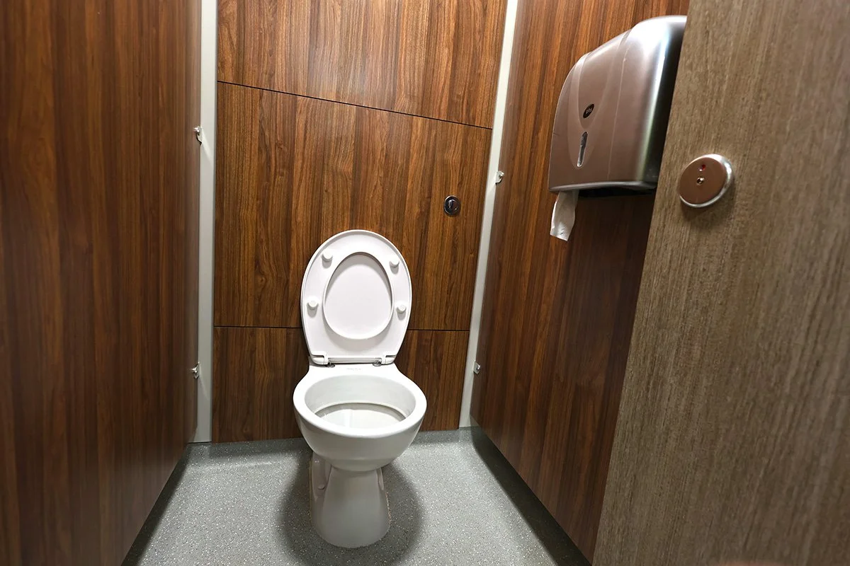Full toilet in cubicle with paper dispenser at holiday park.jpg