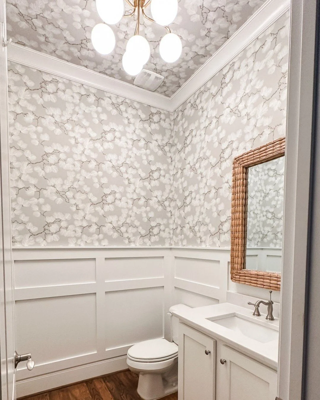 SMALL ROOM WITH A BIG IMPACT. A bold wallpaper was the starting point for this powder room transformation. Once the wallpaper was chosen, everything else clicked into place. 

Oversized seagrass mirror provides texture and leans into the organic, ele