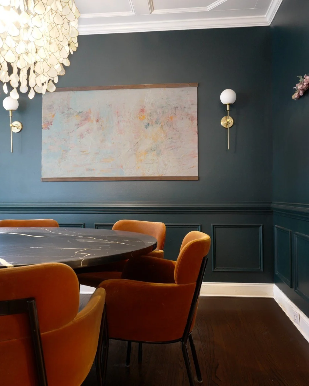 A PERFECT FIT. This dining room was designed to make a statement. Deep, moody wall color sets the tone for a fun night in, and this custom dining table perfectly fit the room's footprint. And this show-stopping chandelier adds the perfect amount of d