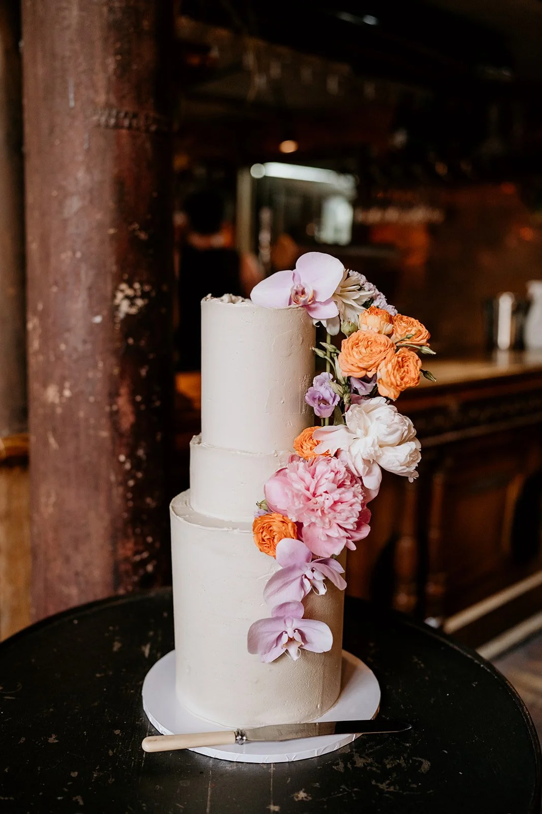 Three-tier white cake with pink and orange flowers