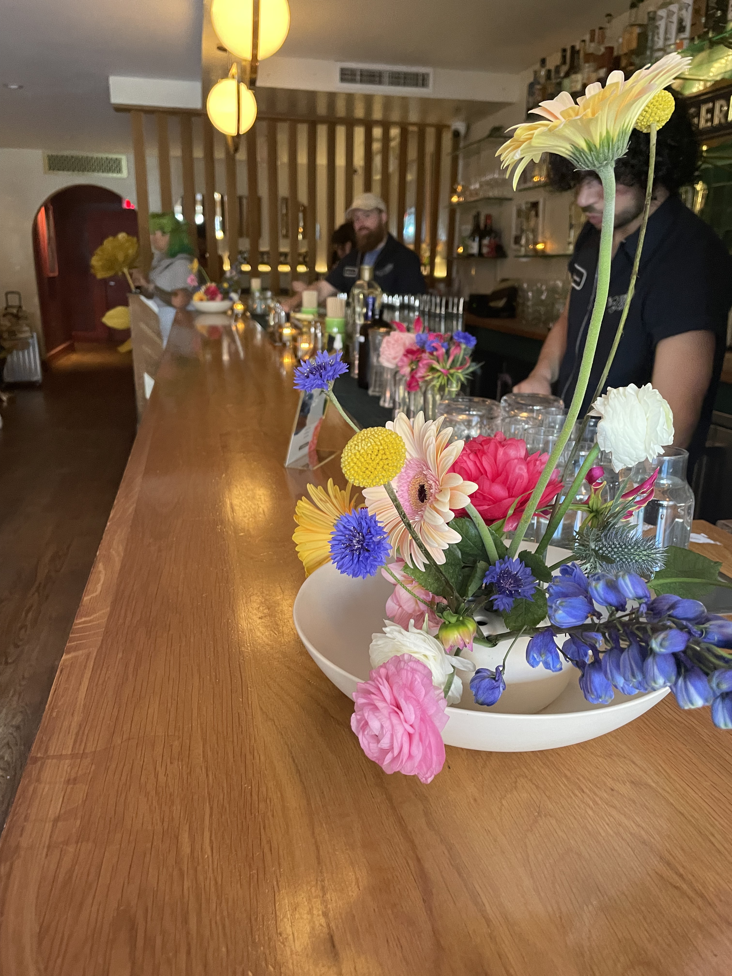 A unique floral arrangement with pink, purple, yellow and white flowers on a bar