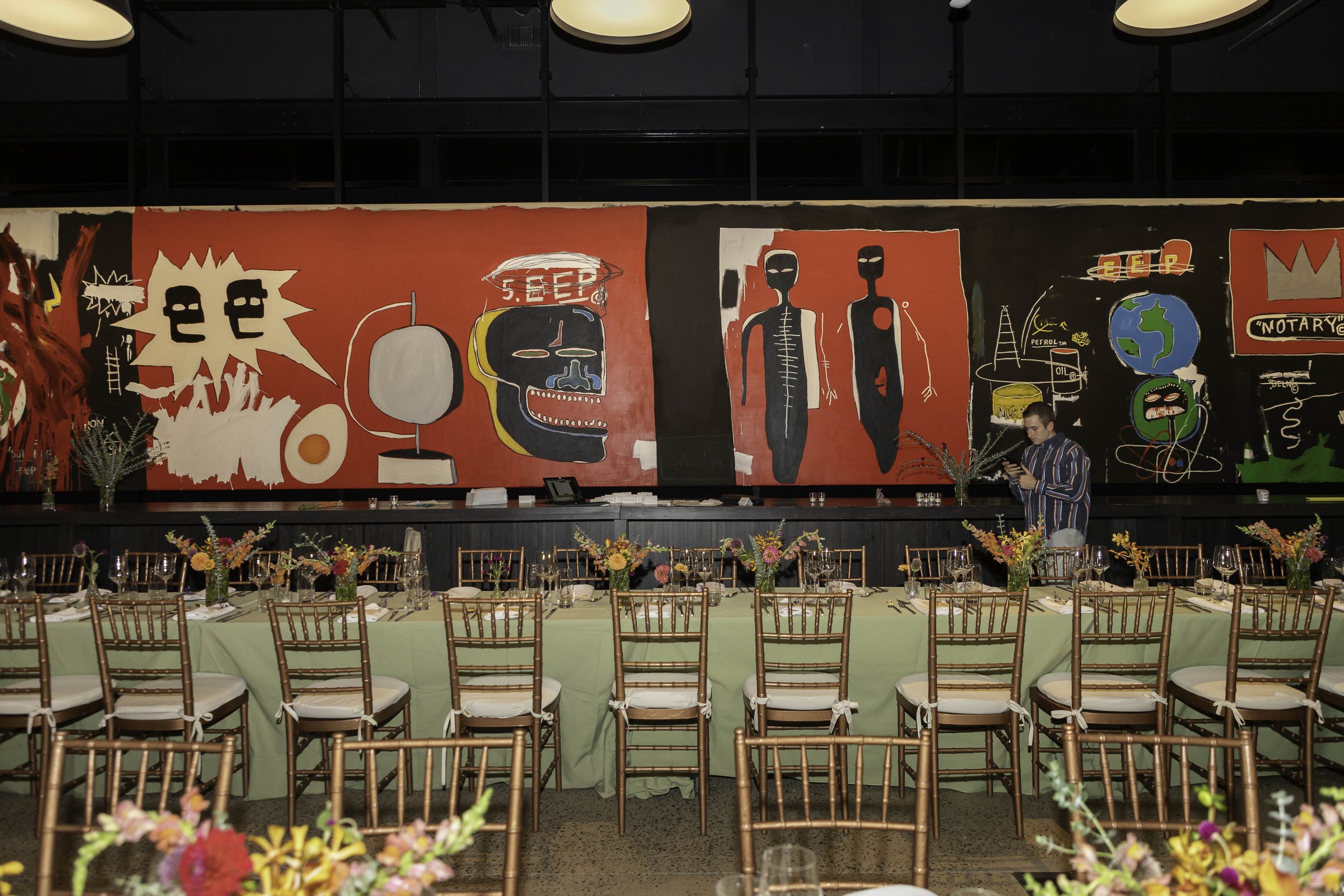 A table setting with Basquiat art in the background