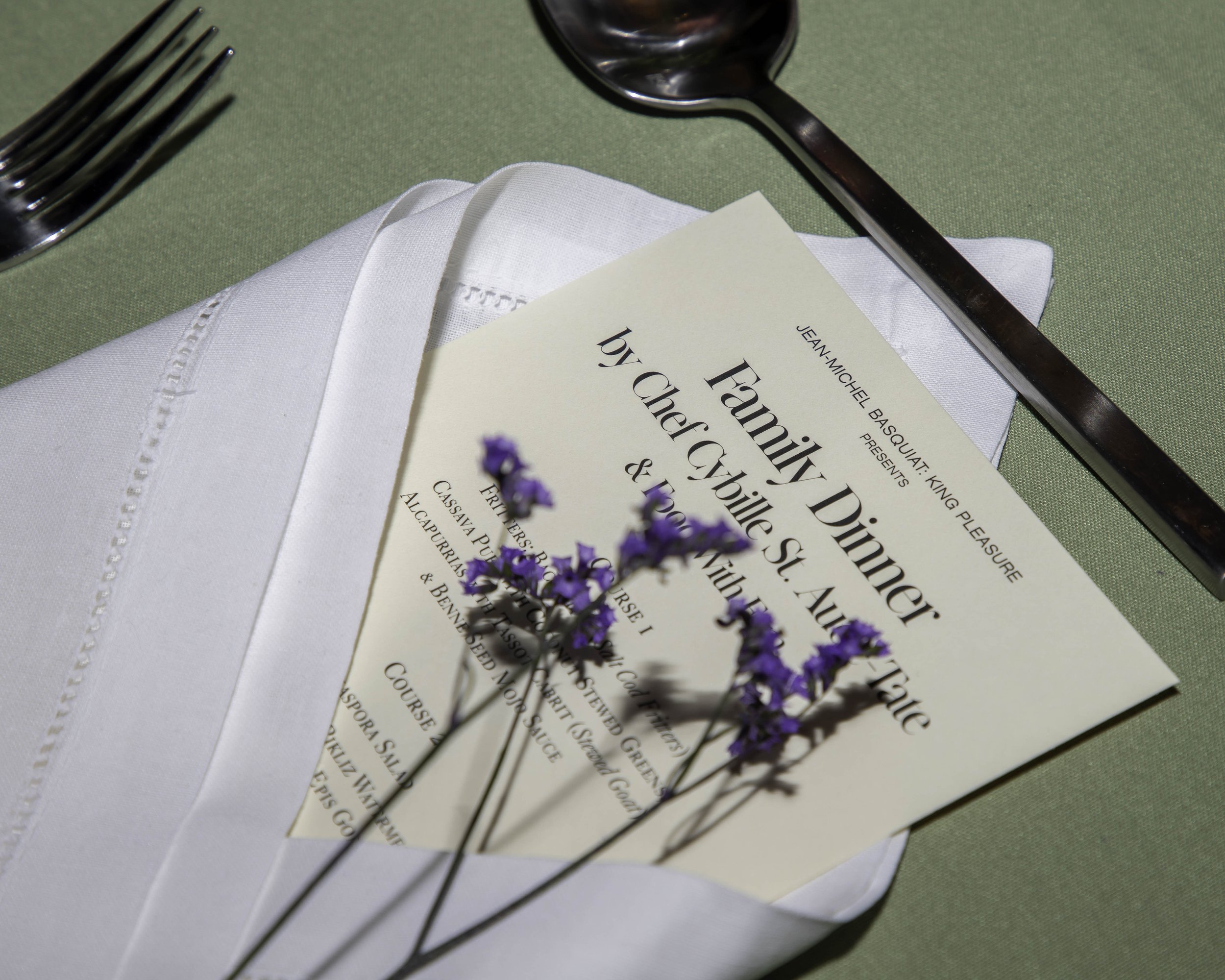 A Printed menu for the event wrapped in napkin with small purple flowers on top