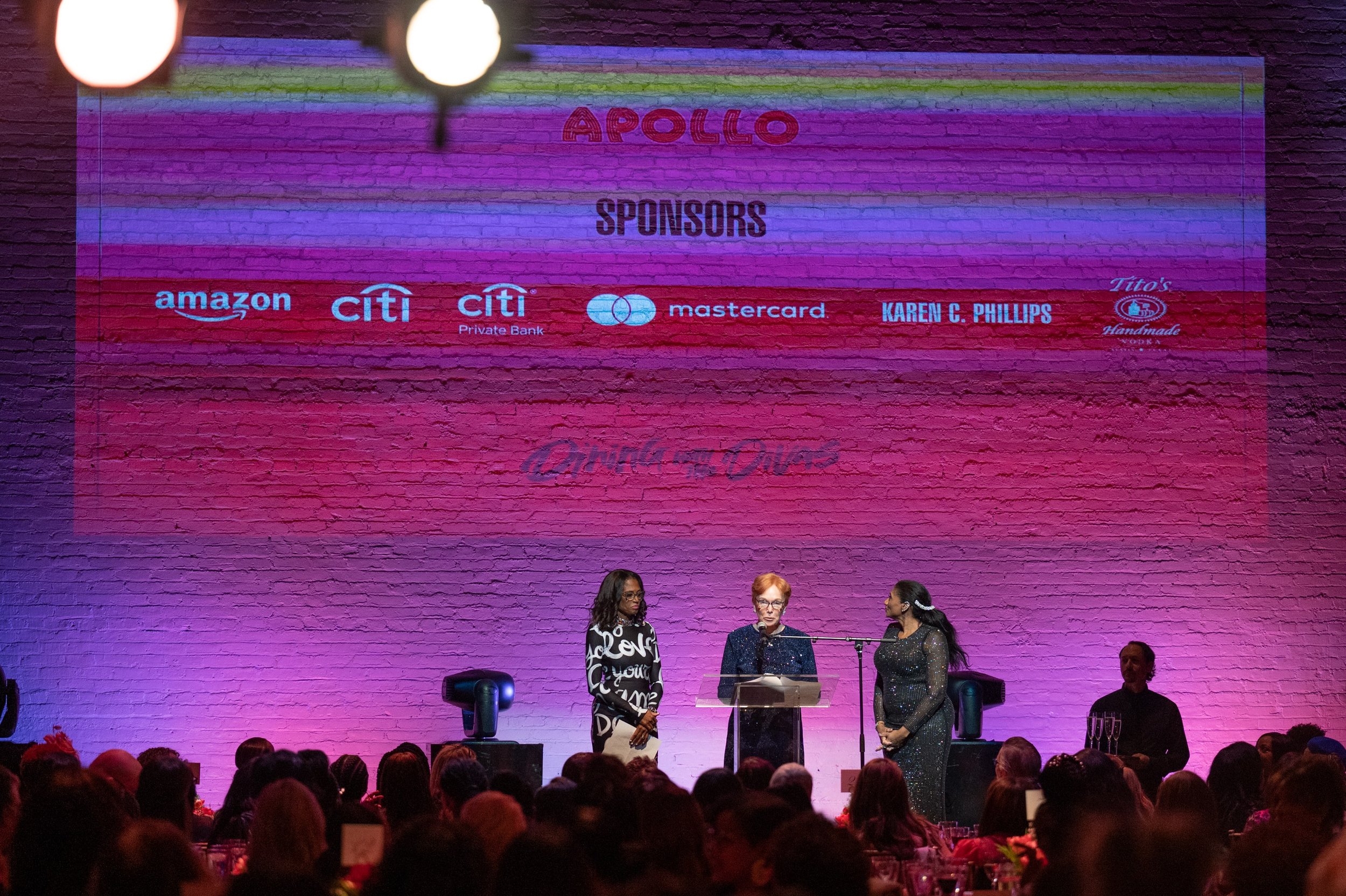 Three women on stage presenting an award