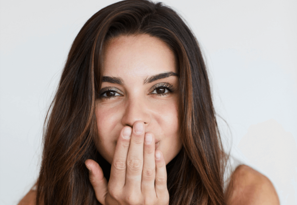 Woman covering her mouth. Discusses how profanity can mask vulnerability and the self-acceptance gained through IFS Therapy in St. Louis.