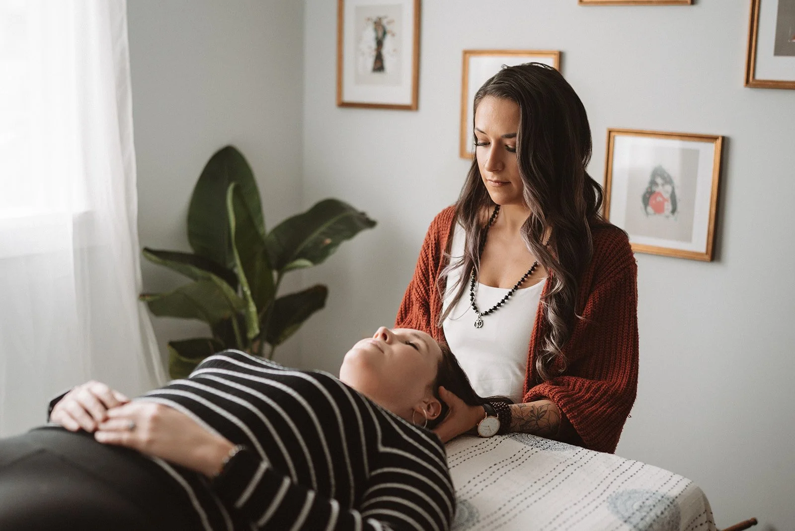 Woman receiving a Reiki energy healing treatment from a practitioner in a treatment room.