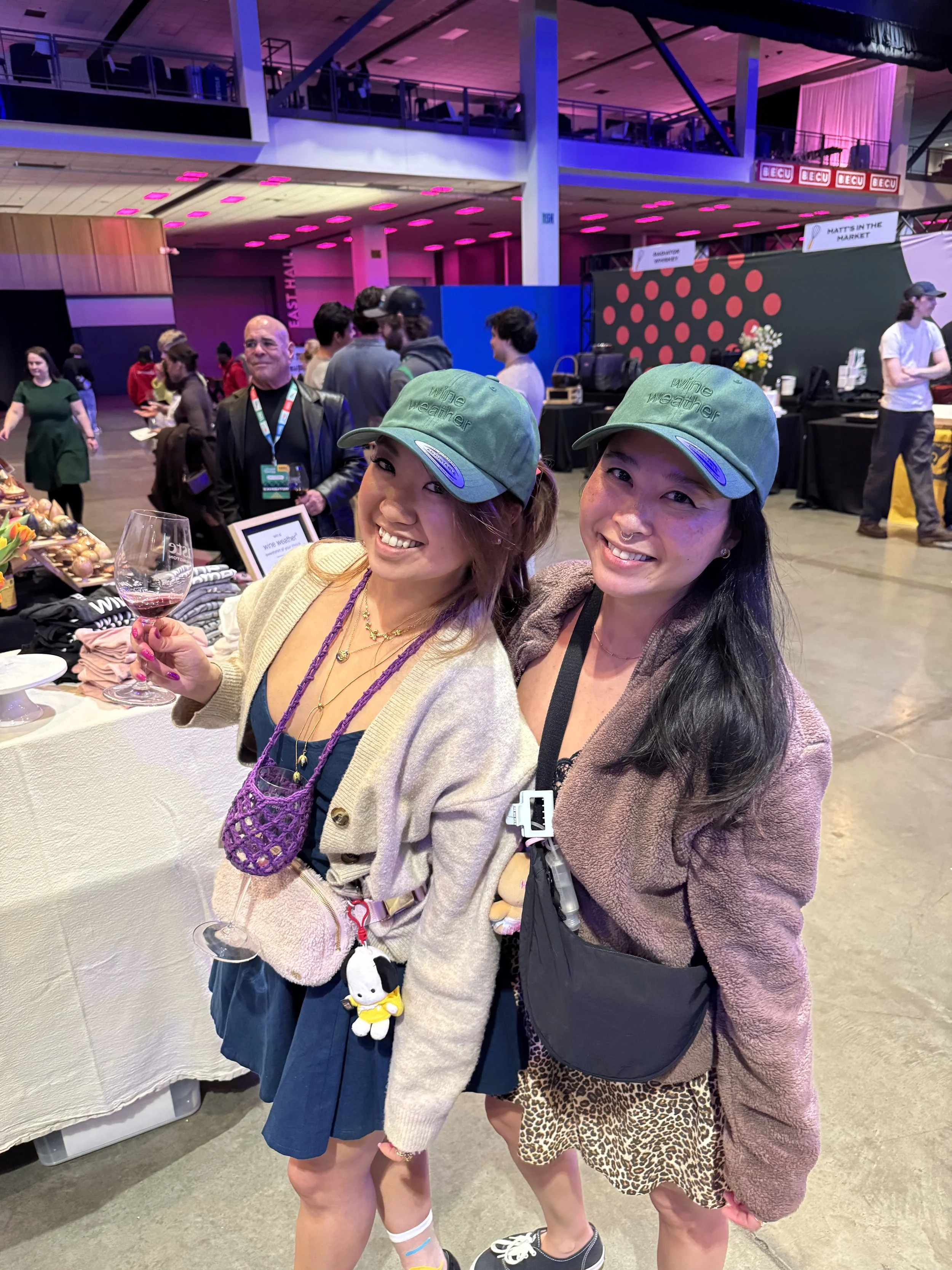 two girls in wine weather® hats enjoying wine at the taste washington event at Lumen Field celebrating washington wine month