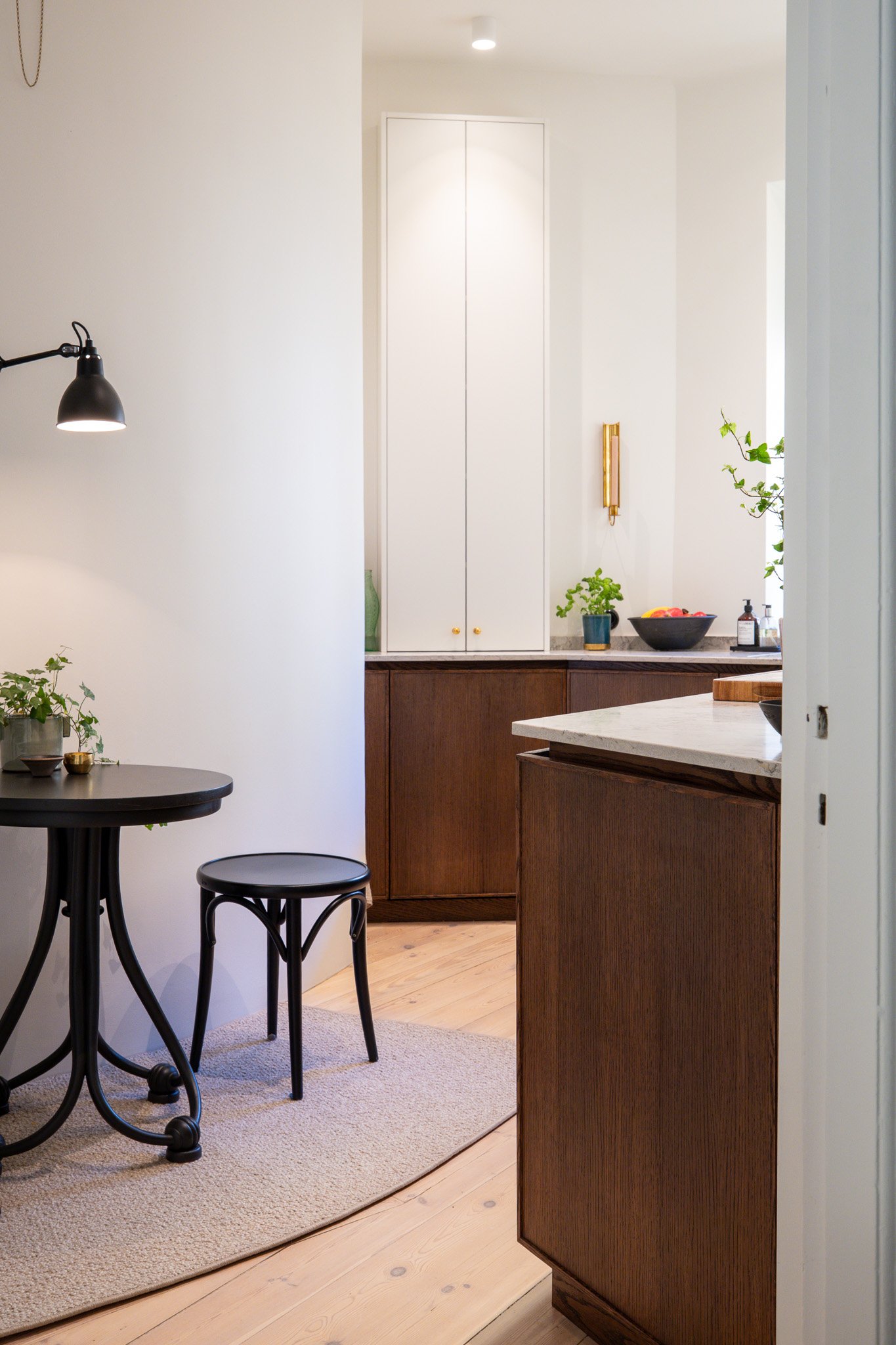 Platsbyggt kök med integrerad förvaring och naturlig övergång till matplats i ljus lägenhet