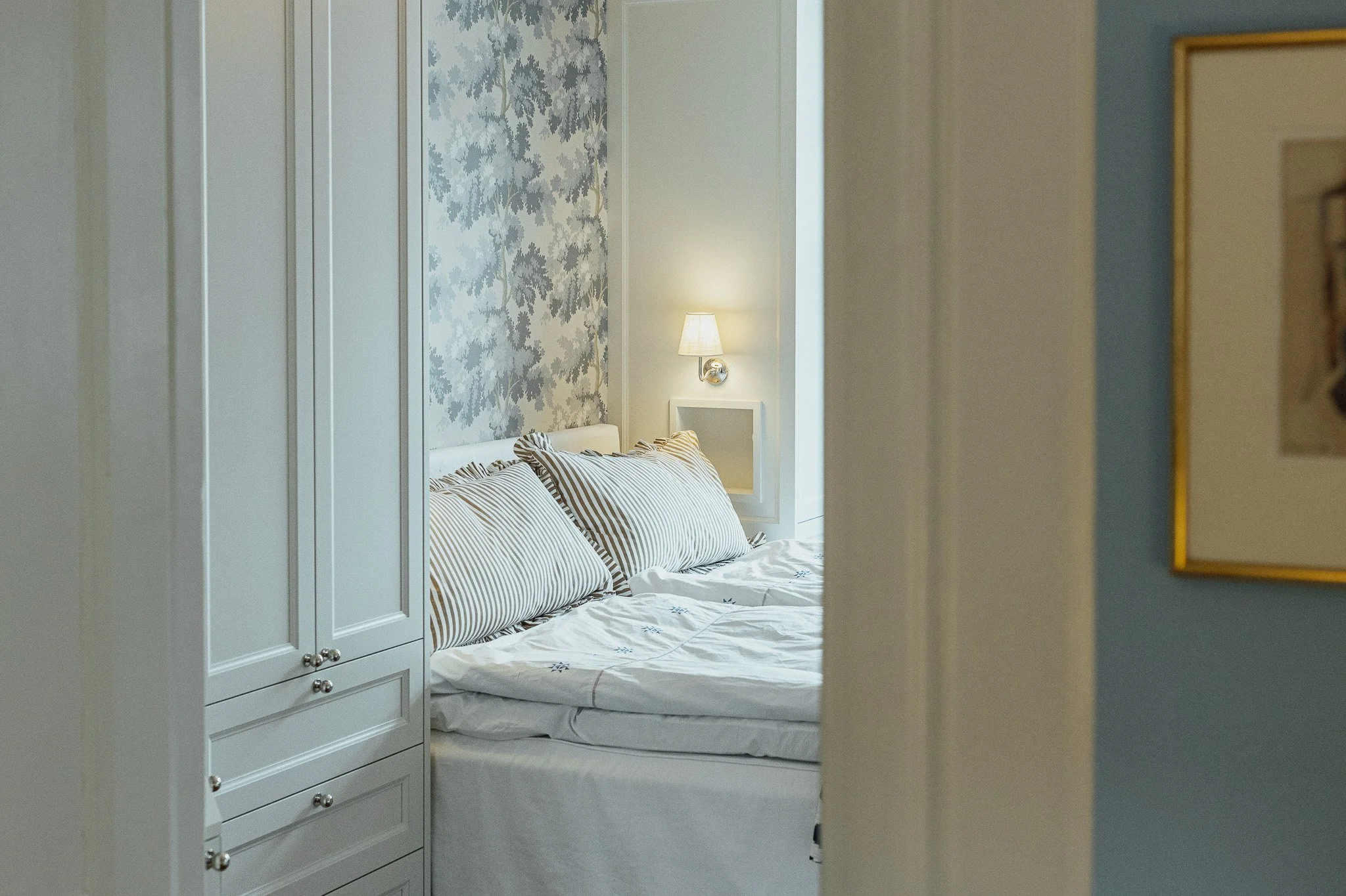 Platsbyggd garderob integrerad runt säng med smart förvaring och klassisk design