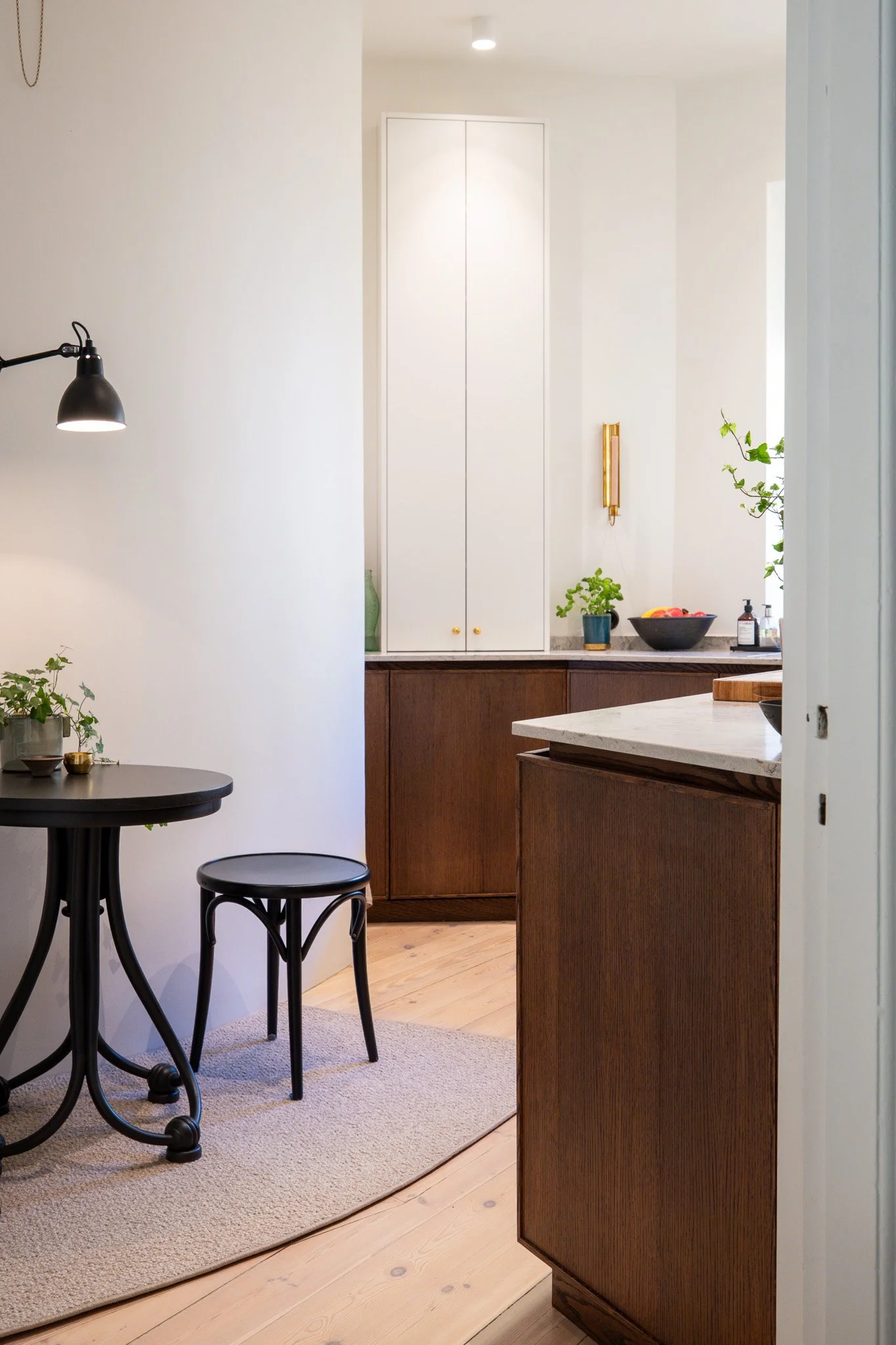 Platsbyggt kök i Stockholm med integrerad förvaring och övergång till matplats i trä och sten