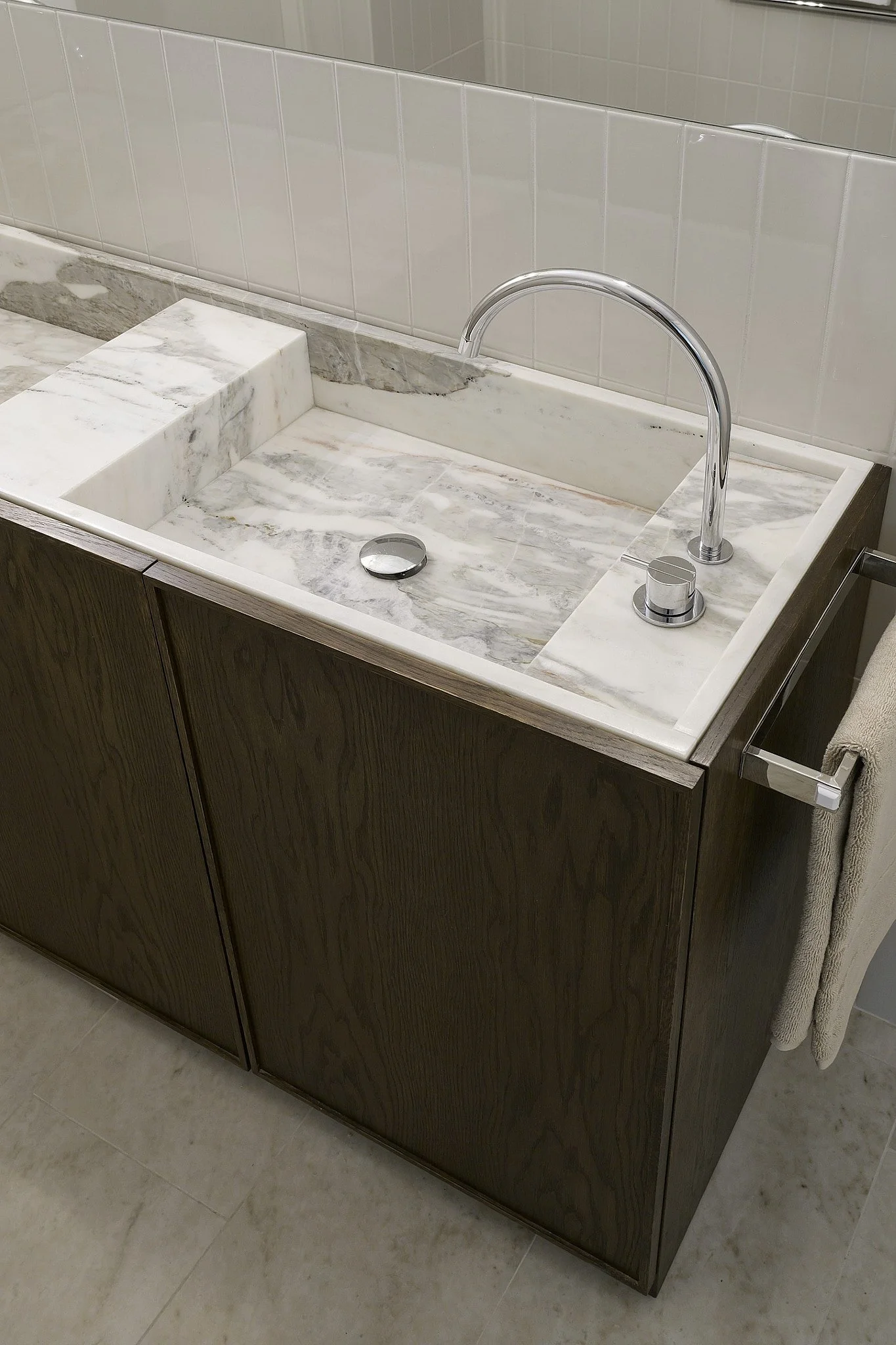 Detalj av badrumskommod med integrerat marmortvättställ och mörkbetsad ek