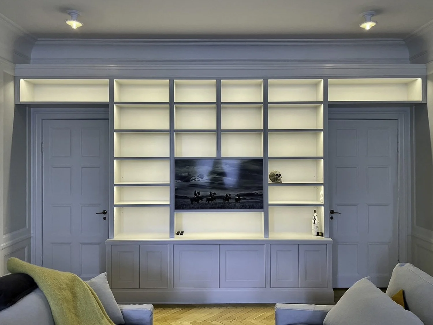 Platsbyggd TV-vägg med bokhylla och integrerad LED-belysning som smälter in i rummets arkitektur