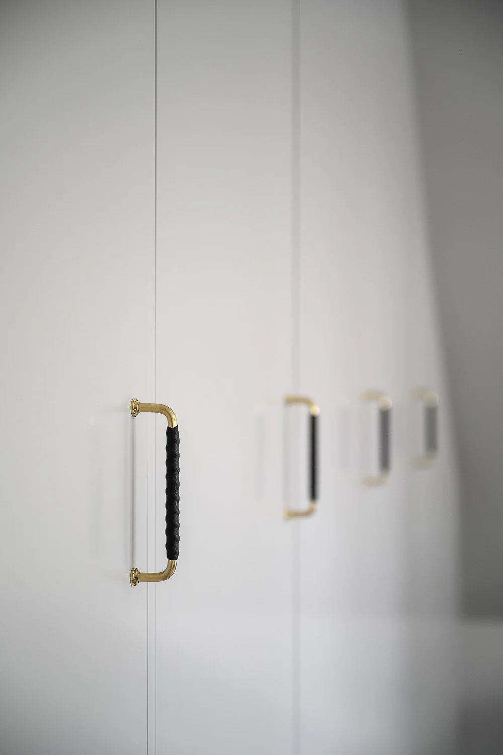 Massingshandtag med lindat lader pa vit garderobsdorr – tidlos detalj i Djursholm.