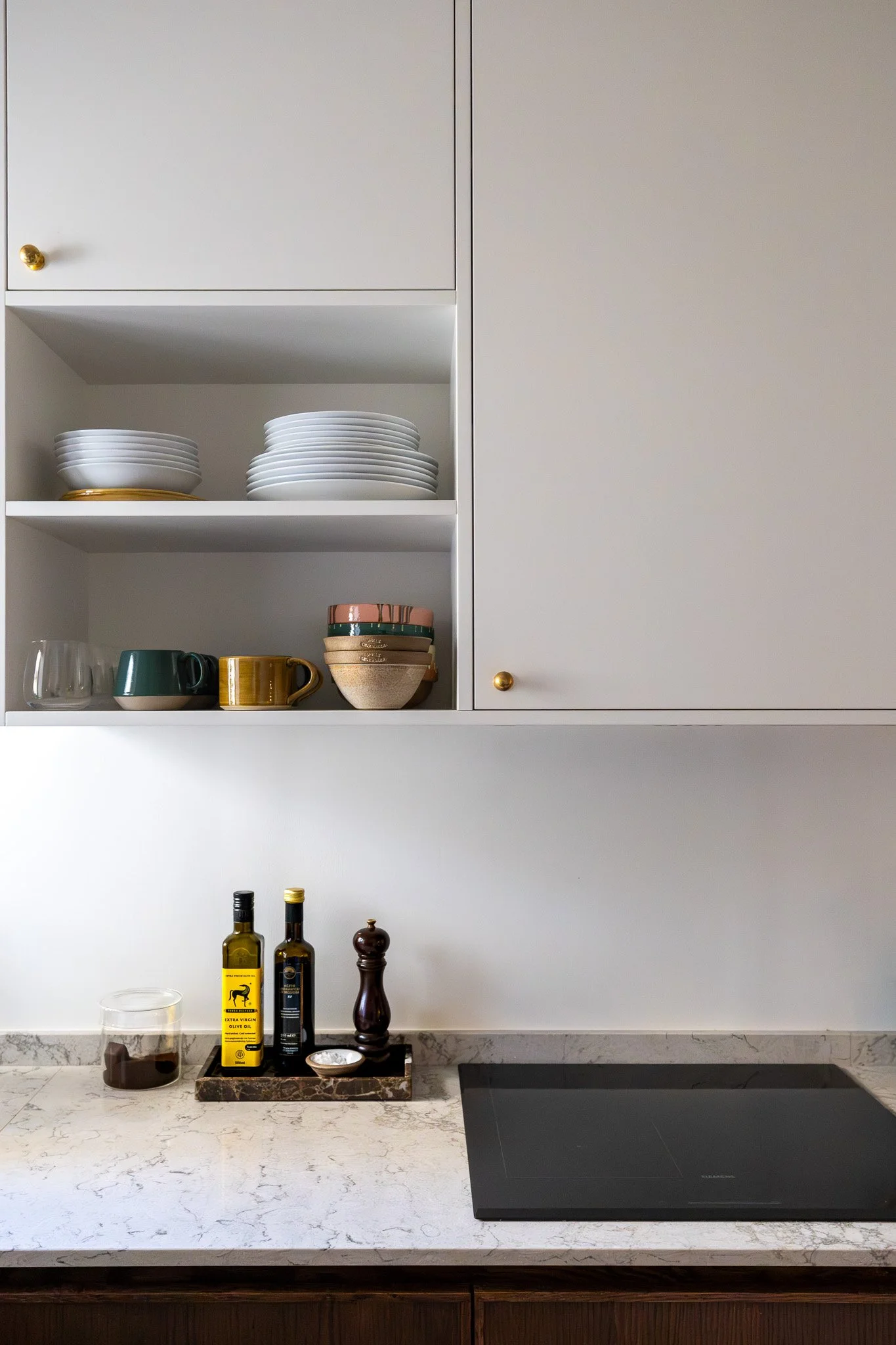 Detalj av platsbyggt kök med öppna hyllor, stenbänkskiva och klassiska materialval