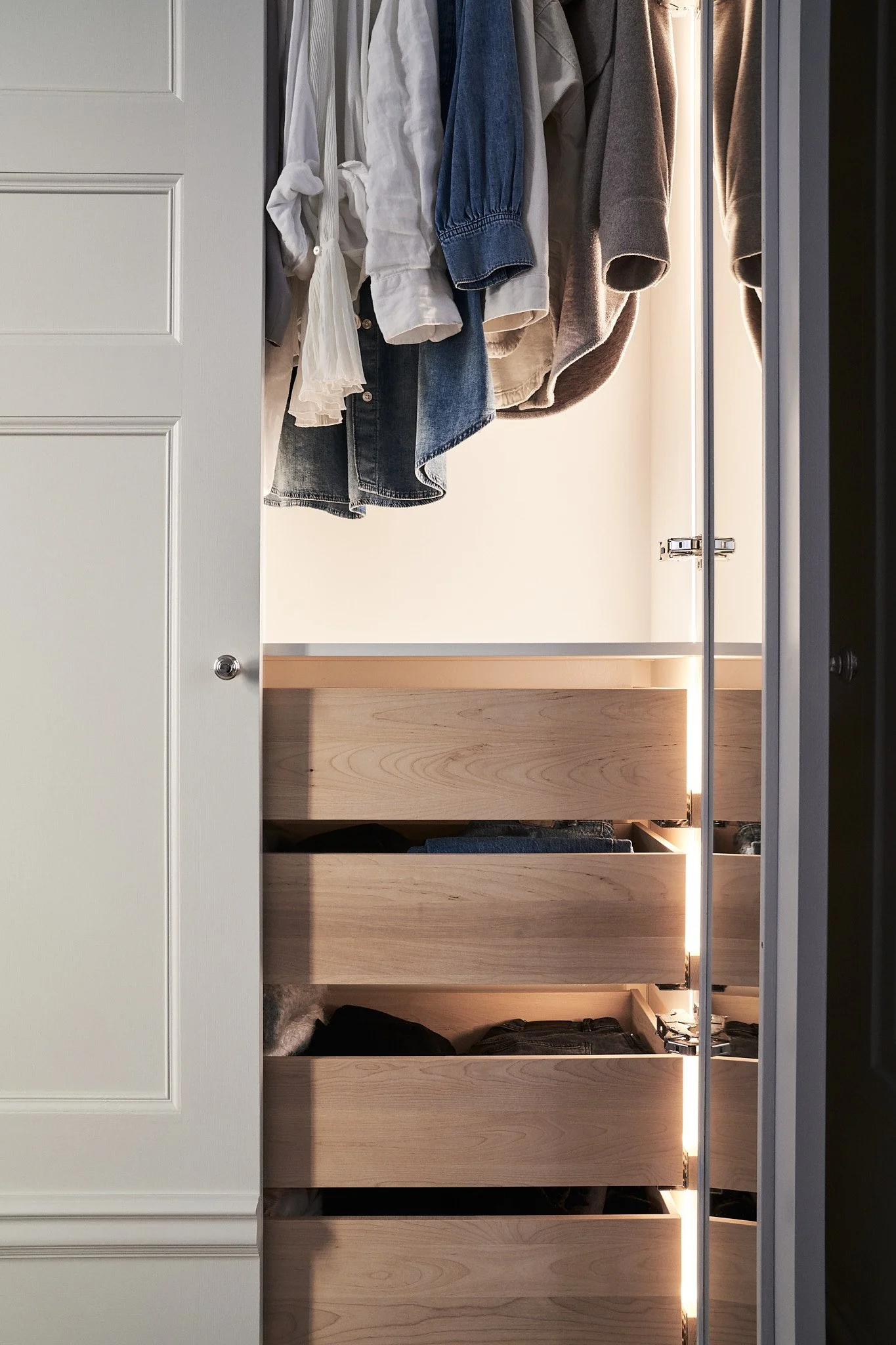 Detalj av platsbyggd garderob med trä-lådor och integrerad belysning i sekelskifteslägenhet på Södermalm Stockholm
