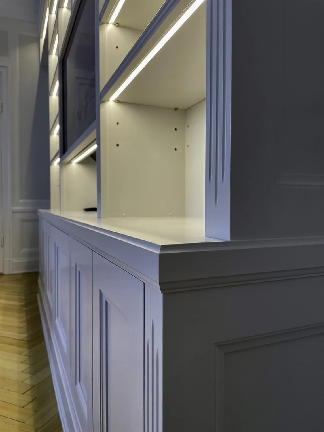 Detalj av platsbyggd bokhylla med integrerad LED-belysning och TV-lösning i vardagsrum