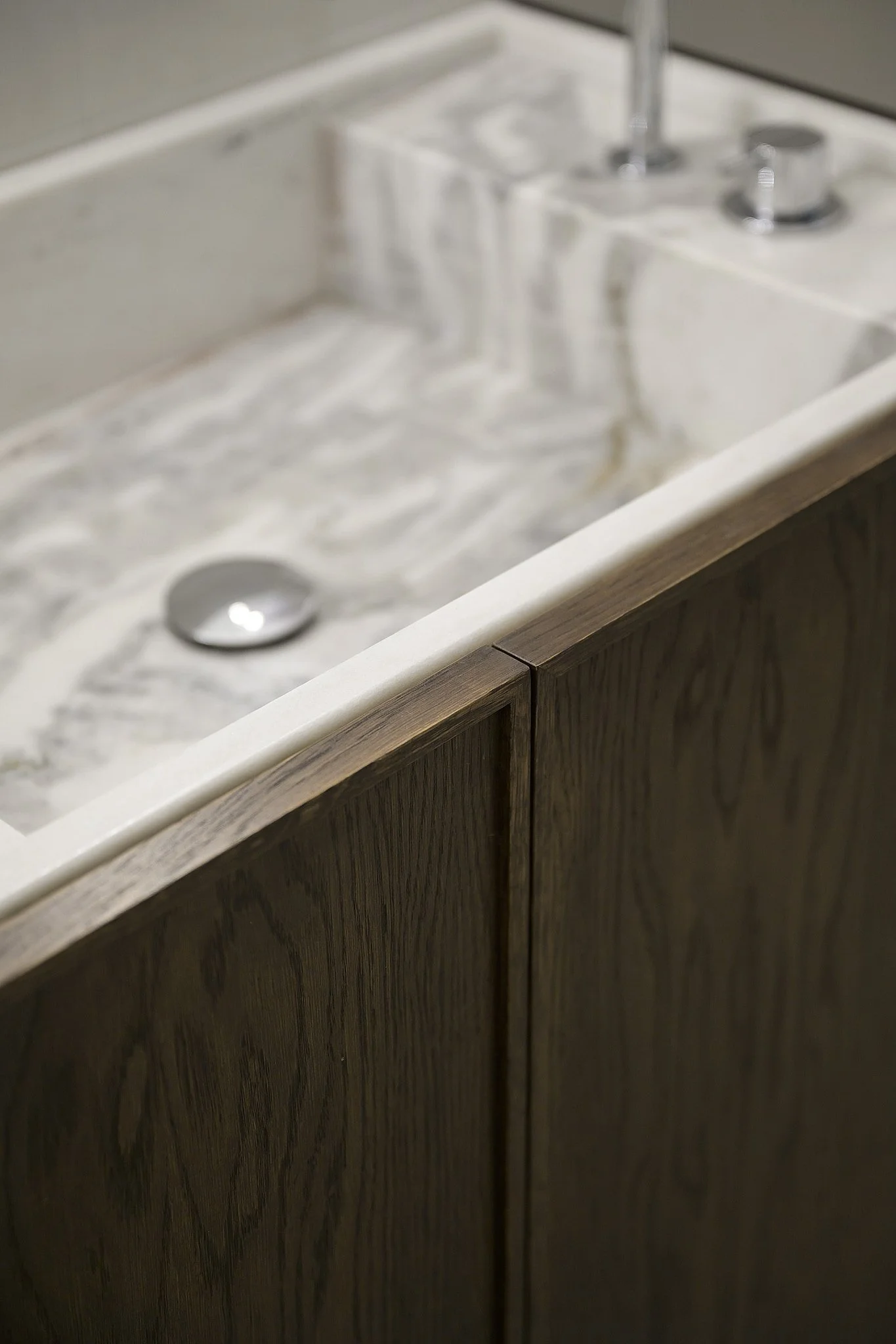 Detalj av platsbyggd badrumskommod i mörkbetsad ek med marmorskiva