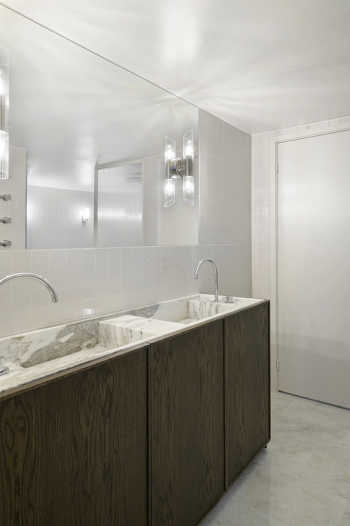 Badrum med platsbyggd kommod i mörk ek, marmorskiva och spegel med väggbelysning