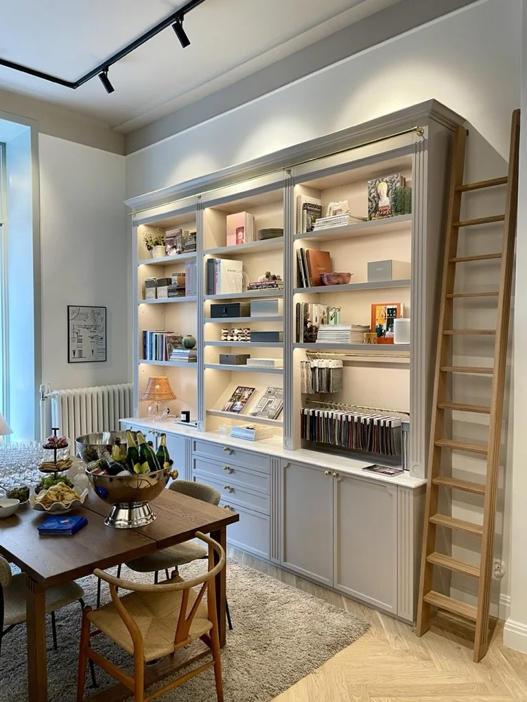 Platsbyggd bokhylla med stege och varm belysning i showroom i Vasastan.