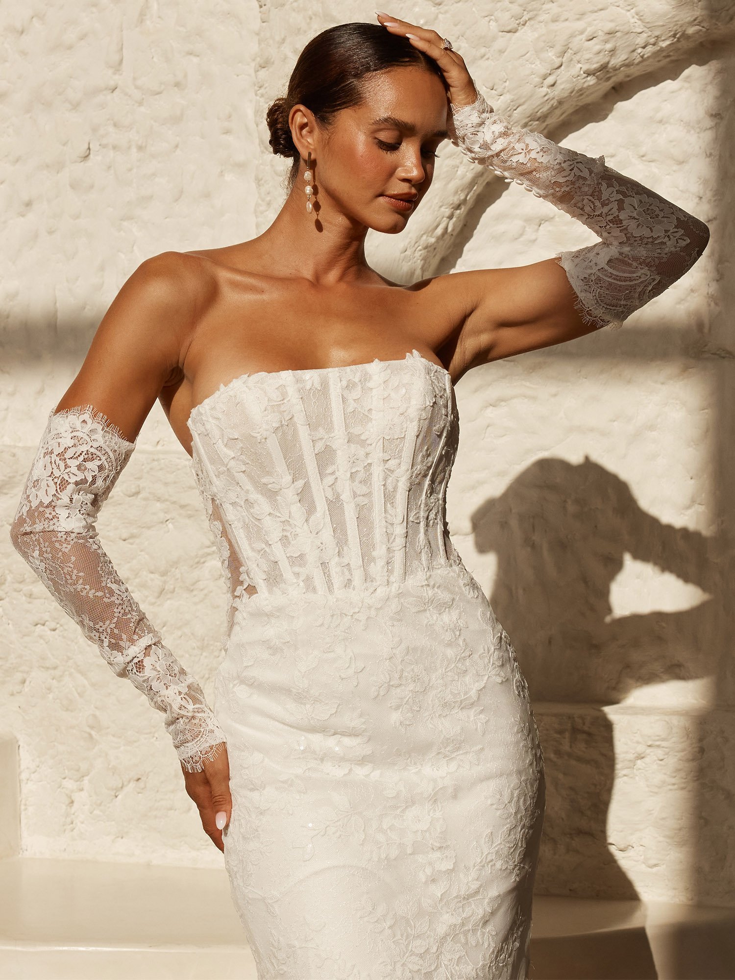 A strapless Chantilly lace wedding dress with detachable off-shoulder sleeves, illusion lace panels, modern boning detail, and a slim-line skirt that flares at the knee into a shaped lace train.