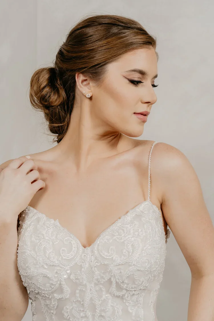 Bride in a beaded lace mermaid wedding gown with spaghetti straps, sweetheart neckline, low open back, and scalloped cathedral train.
