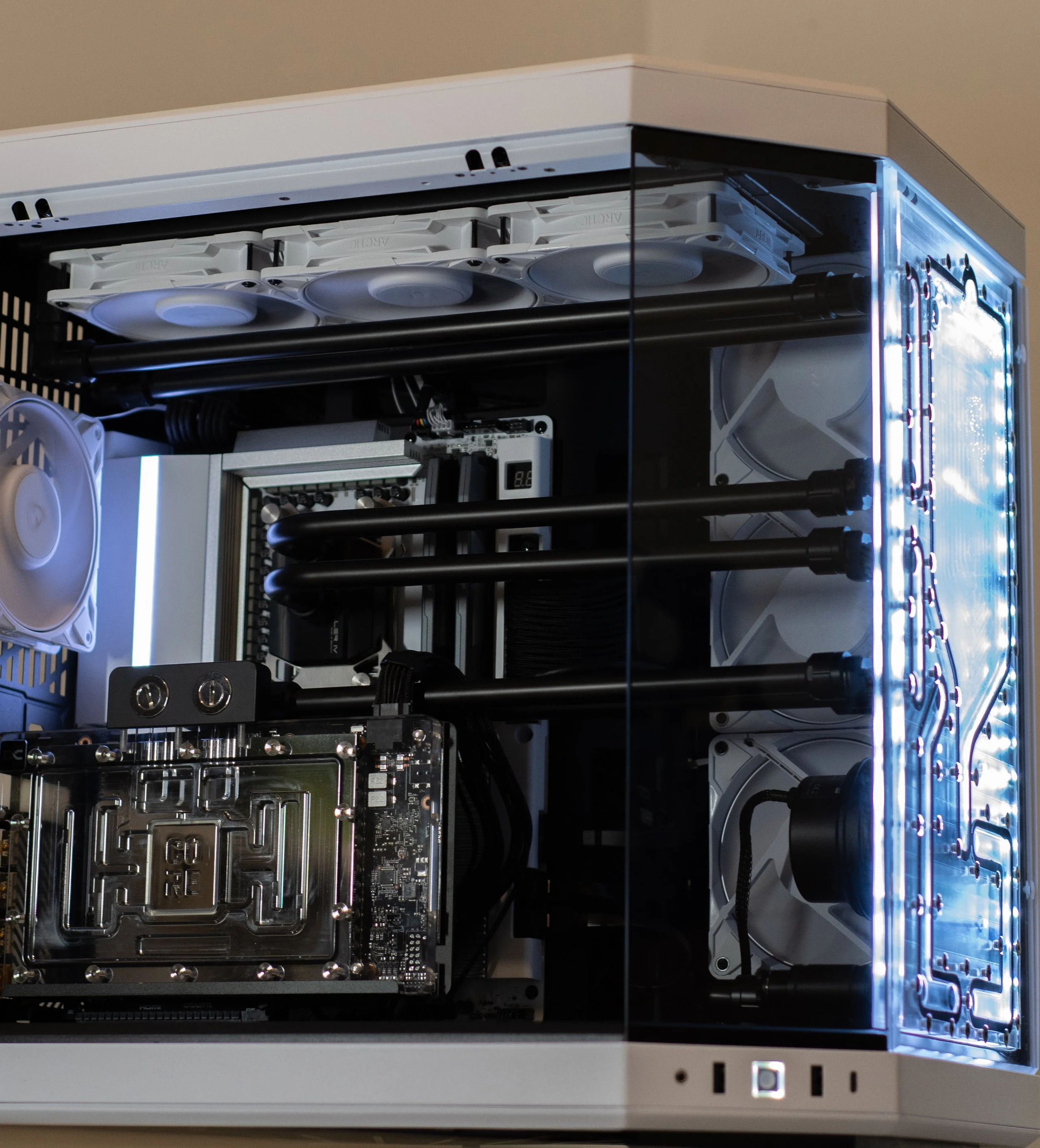 A custom-built desktop computer with a transparent side panel, showing internal components including cooling fans, liquid cooling tubes, a motherboard, and RAM, illuminated by blue LED lights.