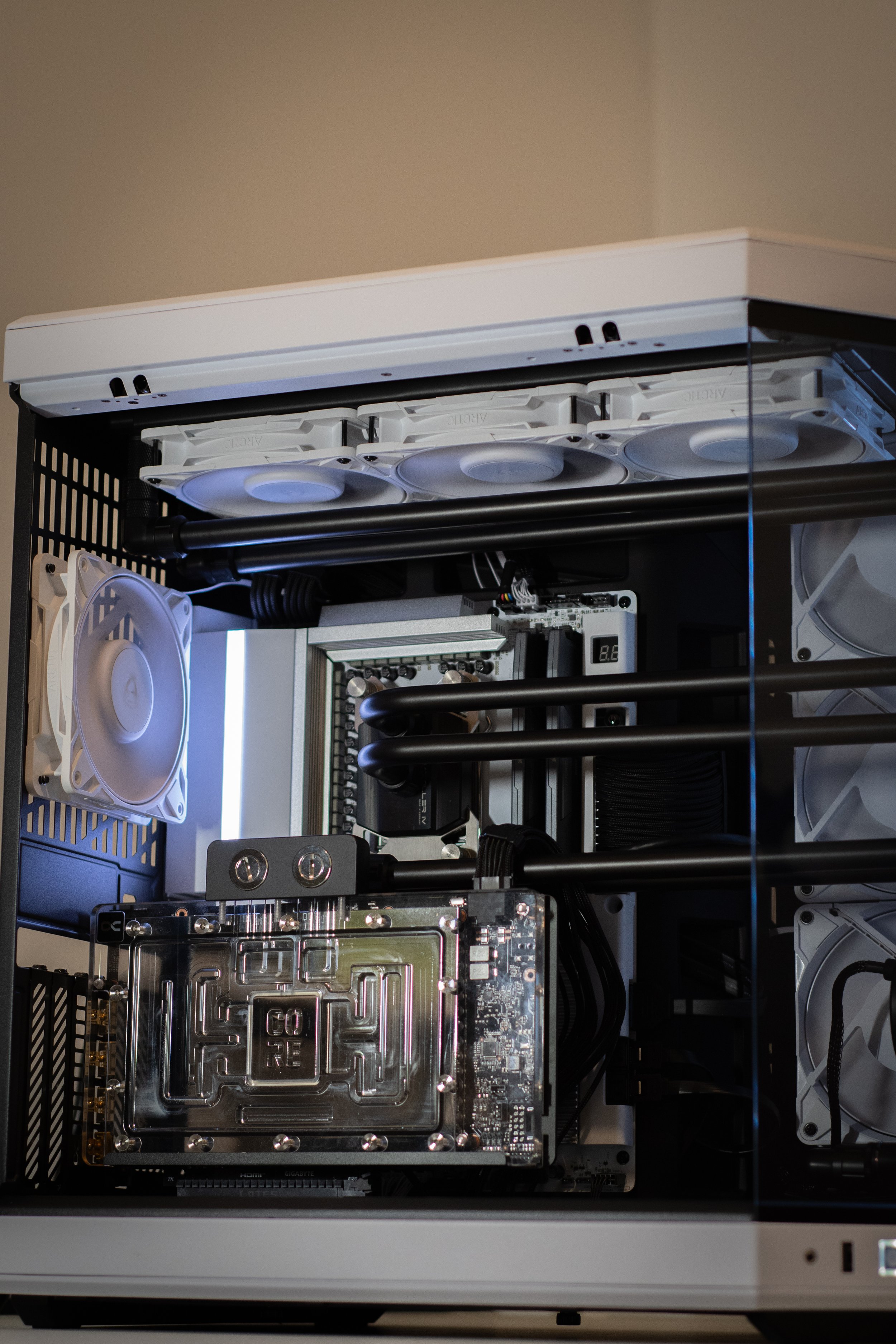 A custom-built gaming computer inside a white case with multiple cooling fans, a liquid cooling system with black tubes, a large graphics card, and various internal components visible.