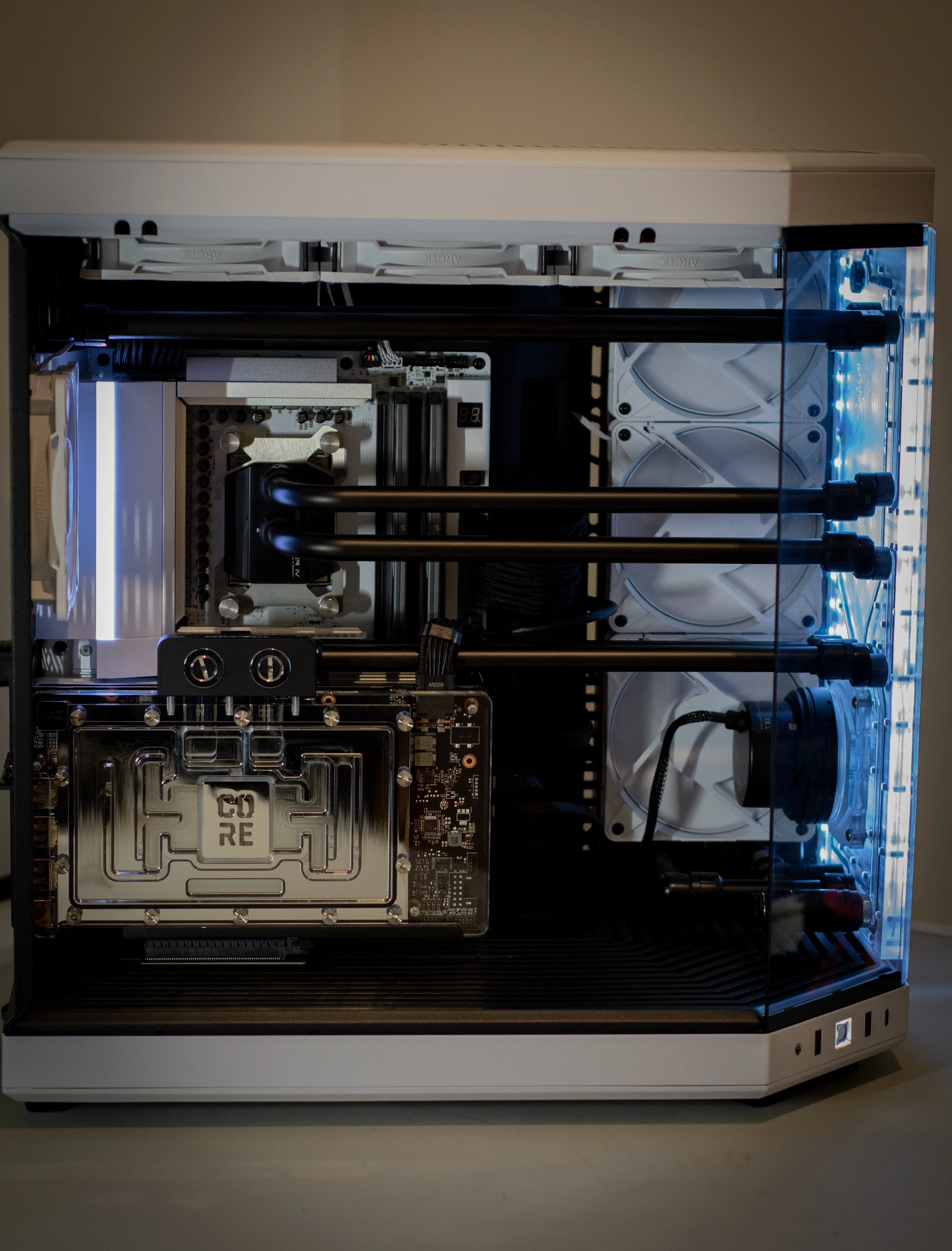 A custom-built desktop computer with a water cooling system featuring multiple radiators, fans, and a graphics card, housed in a white and black case with LED lighting.