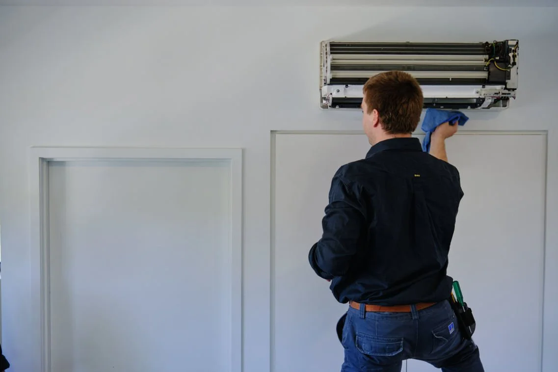 Aircon Cleaning in Brisbane, Man cleaning and aircon in Brisbane by taking it apart and pressure cleaning the entire unit.