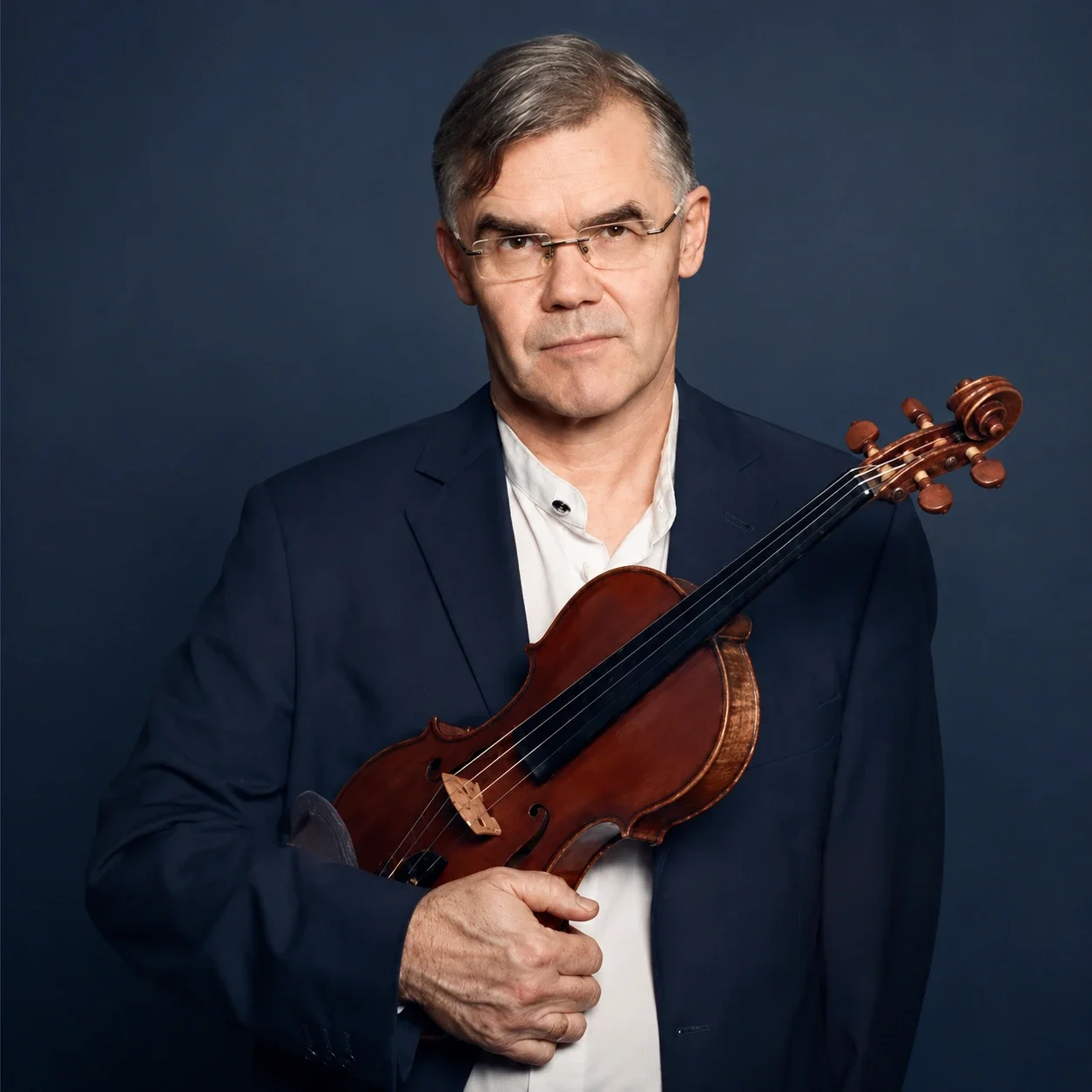 Paul Wright standing in front of a blue background holding a violin.