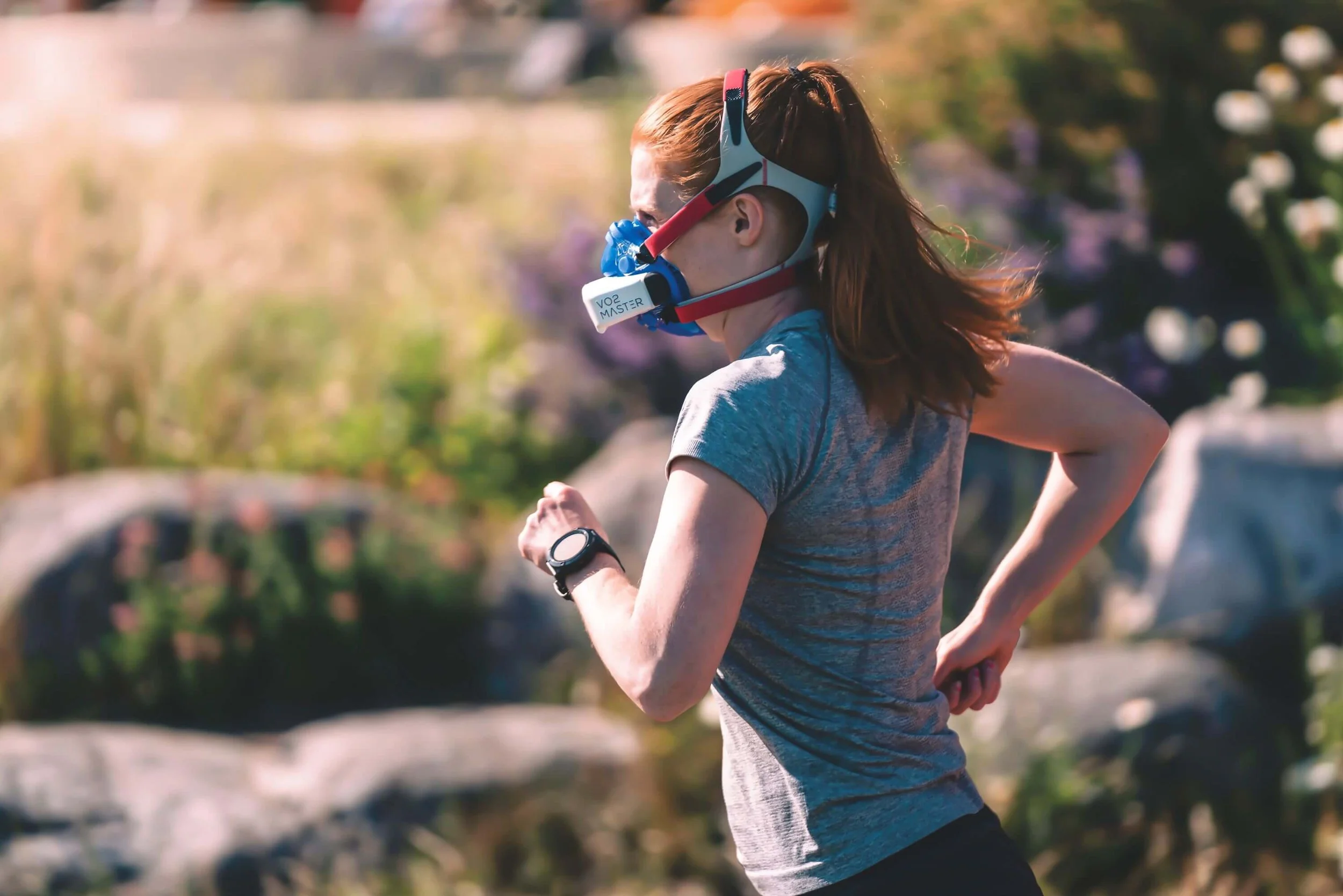 Vrouw jogt in de natuur met een sportmasker, ze doet aan IHHT hypoxische ademtraining.